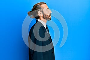 Attractive man with long hair and beard wearing business suit and tie looking to side, relax profile pose with natural face with