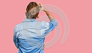 Attractive man with long hair and beard wearing casual denim jacket backwards thinking about doubt with hand on head
