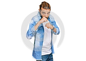 Attractive man with long hair and beard wearing casual denim jacket ready to fight with fist defense gesture, angry and upset
