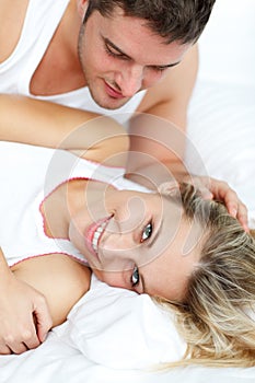 Attractive man looking at his girlfrined in bed