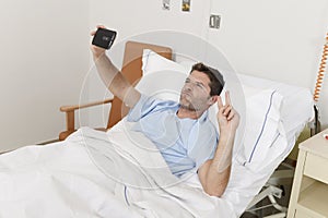 Attractive man lying on bed hospital clinic holding mobile phone taking self portrait selfie photo