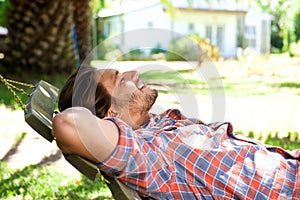 Attractive man lying down in hammock in back yard