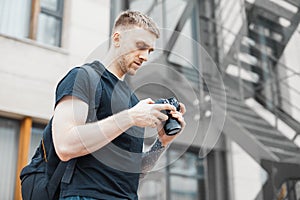 Attractive man next to staircase and checking photos in camera.