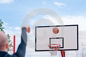 Attractive man playing basketball and dunking basketball in hoop on basketball court