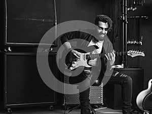 Attractive man playing an electric guitar in a studio