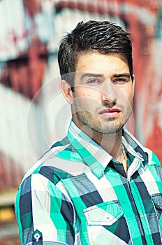 Attractive man posing outdoor over graffiti wall