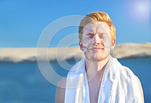 Attractive man with protective sun cream (solar cream, sunscreen)  on the face for care of his body.