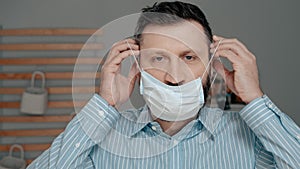 Attractive man puts on surgical mask on his face. Cold, flu, virus, acute respiratory infections, quarantine, epidemic, irony,