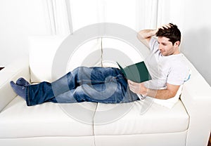 Attractive man reading book or studying on couch