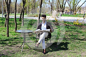 Attractive man reading newspaper in park, slow motion.