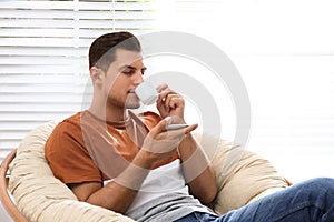 Attractive man relaxing in papasan chair near window