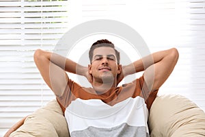 Attractive man relaxing in papasan chair near window