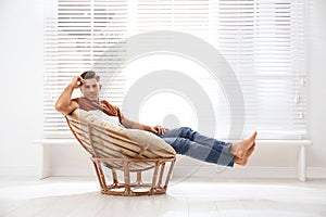 Attractive man relaxing in papasan chair near window