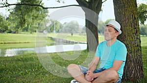 Attractive man resting while sitting under a tree, tracking by camera