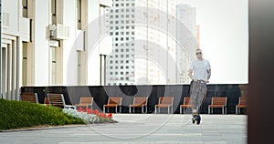 Attractive man riding electric kick scooter at cityscape background