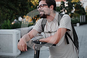 Attractive man riding a kick scooter at cityscape background