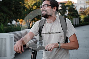 Attractive man riding a kick scooter at cityscape background