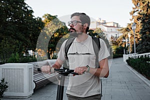 Attractive man riding a kick scooter at cityscape background