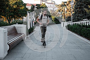 Attractive man riding a kick scooter at cityscape background