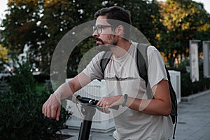 Attractive man riding a kick scooter at cityscape background