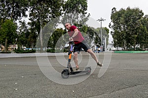 Attractive man riding a kick scooter at cityscape background