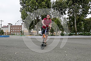 Attractive man riding a kick scooter at cityscape background