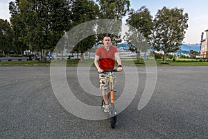 Attractive man riding a kick scooter at cityscape background