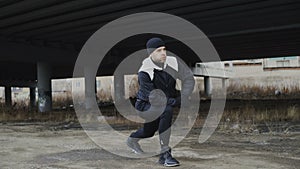 Attractive man runner doing stretching exercise for morning workout and jogging at urban location outdoors in winter