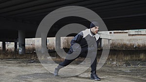 Attractive man runner doing stretching exercise for morning workout and jogging at urban location outdoors in winter