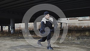 Attractive man runner doing stretching exercise for morning workout and jogging at urban location outdoors in winter