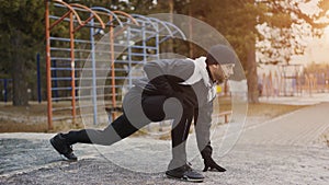 Attractive man runner doing stretching exercise preparing for morning workout and jogging in winter park