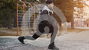 Attractive man runner doing stretching exercise preparing for morning workout and jogging in winter park