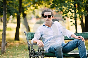 Attractive man sitting alone on the bench with cellphone