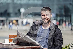 Attractive man is sitting in a coffee shop reading the newspaper