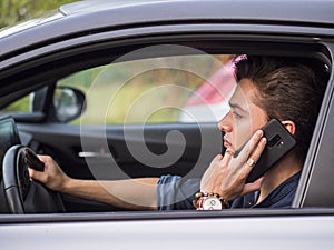 Attractive man sitting in his car talking on cell phone