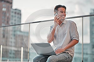 Man on the street. Attractive man sitting outside, using mobile phone and laptop, smiling and looking away