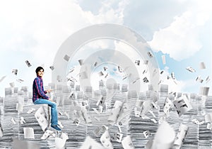 Attractive man sitting on pile of paper documents.