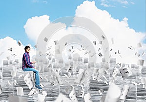 Attractive man sitting on pile of paper documents.