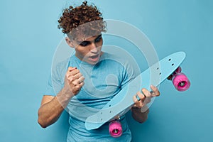 Attractive man skateboard in hand in blue t-shirts blue background