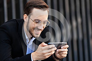 Attractive man smiles and holds smart phone horizontally. Watching video, playing, browsing the Internet