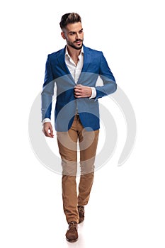 Attractive man in suit buttoning his lounge jacket while walking