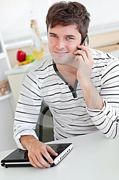 Attractive man talking on phone holding his laptop