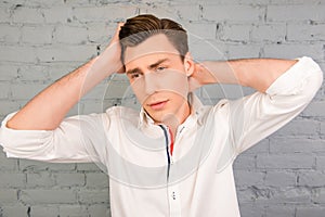 Attractive man touching his hair on the background of gray wall