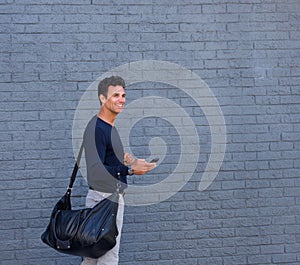 Attractive man walking with mobile phone and bag