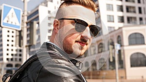 An attractive man wearing black leather jacket with dark sunglasses