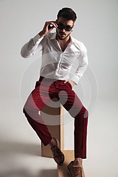 Attractive man wearing unbuttoned shirt fixes his glasses