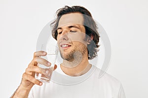 Attractive man in a white T-shirt glass of water isolated background