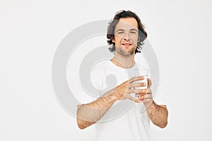 Attractive man in a white T-shirt glass of water isolated background
