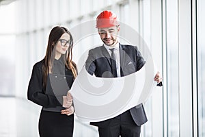 An attractive man and woman business team working construction on the building site near panoramic windows