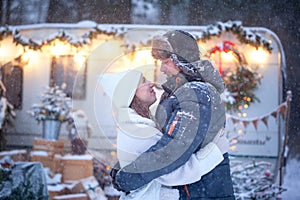 Attractive man and woman cuddling in snowy forest. Adult couple in winter warm clothes have fun on walk. Love story, romantic day